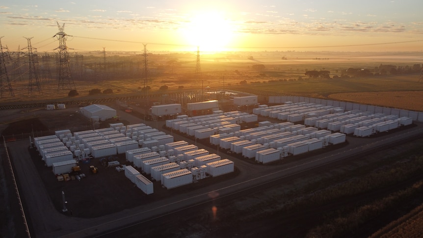 An aerial photo of a giant battery site with the sun shining in the background