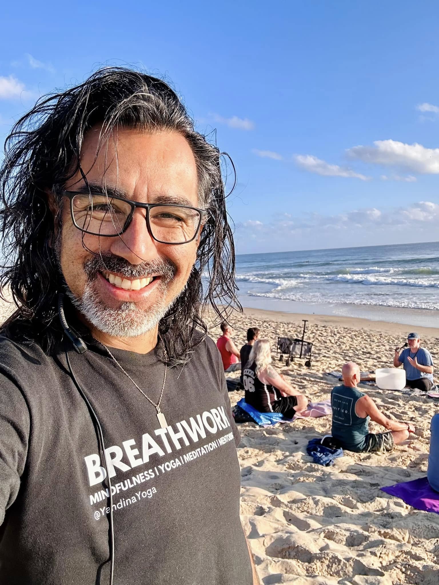 Man smiling at beach with men behind him