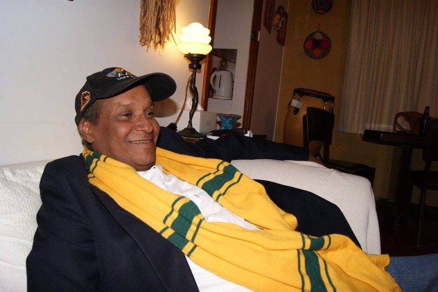 Tahadesse Kahsai sits on a couch, smiling.