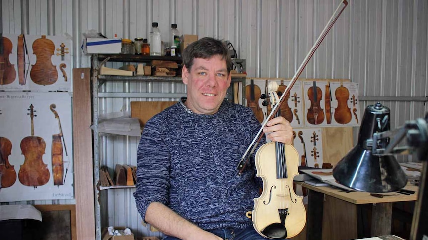 Musician Rob Zielinski hold a violin in his workshop.