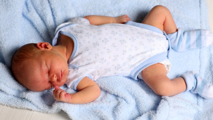 A newborn baby boy lying on his back sleeping.