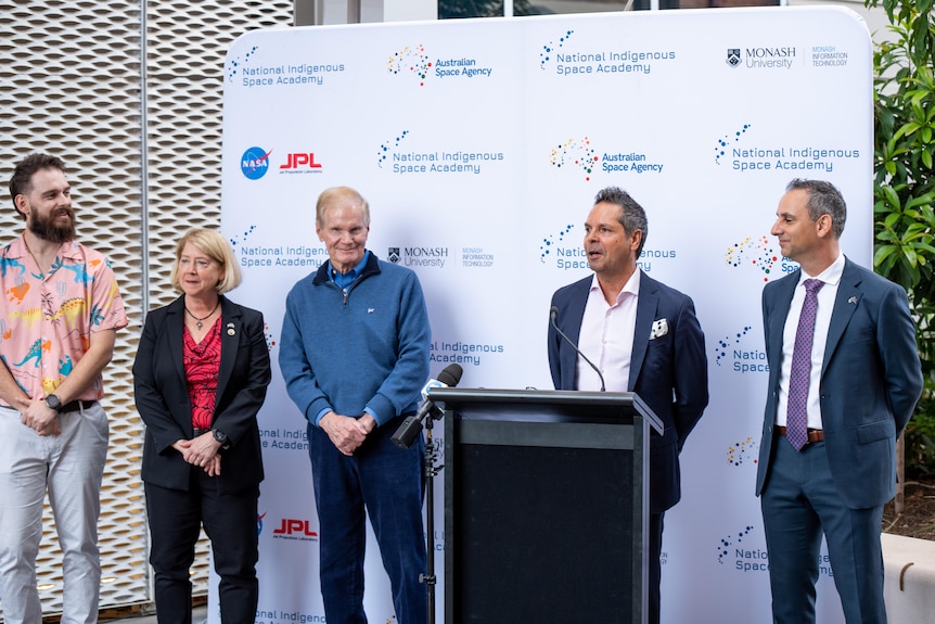 Five people stand behind a lectern.