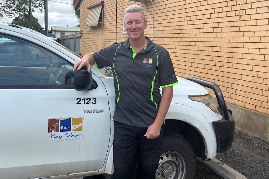 Man in polo shirt standing beside Hay Shire Council ute. 