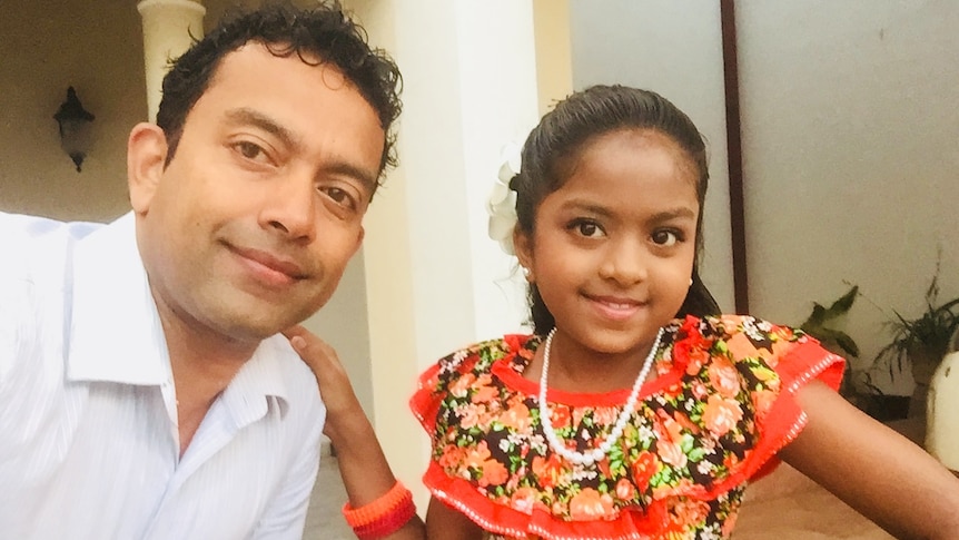 Sudesh Kolonne and his daughter Alexendria, who poses wearing a red frilly dress and a necklace.