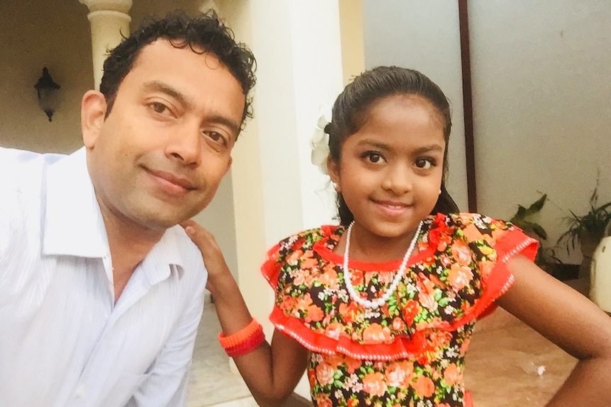 Sudesh Kolonne and his daughter Alexendria, who poses wearing a red frilly dress and a necklace.
