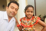 Sudesh Kolonne and his daughter Alexendria, who poses wearing a red frilly dress and a necklace.