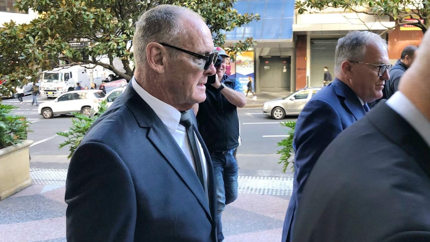 elderly man in suit and sunglasses walking down the street