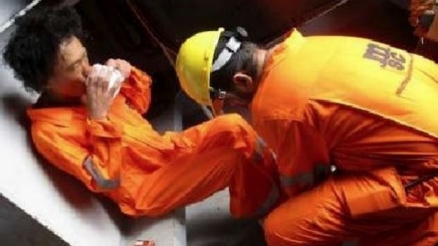 The rescued man sipping a drink in borrowed orange suit.