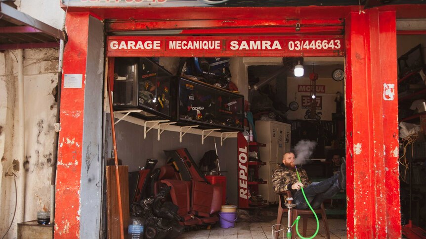 A man smokes in a garage.