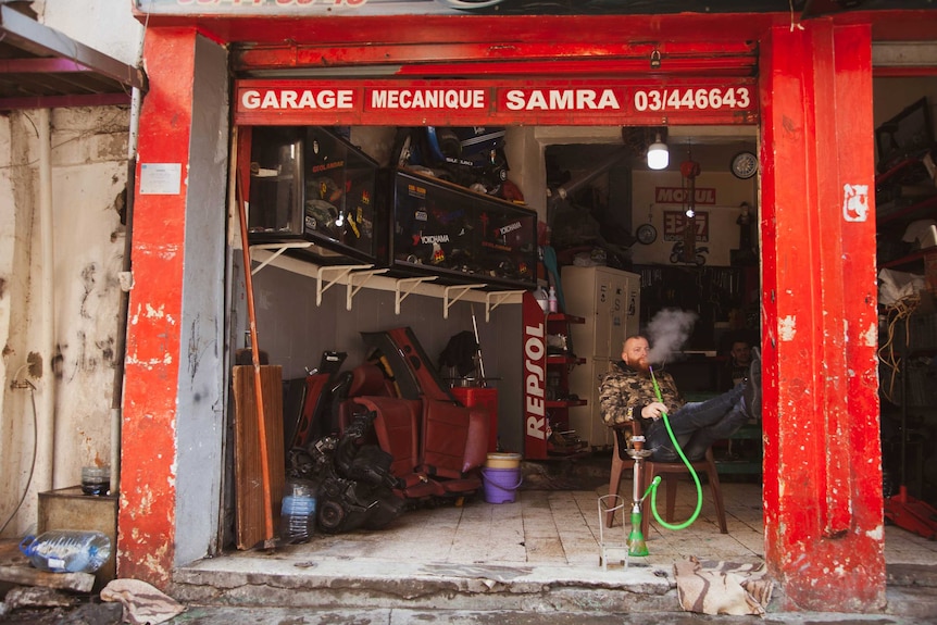 A man smokes in a garage.