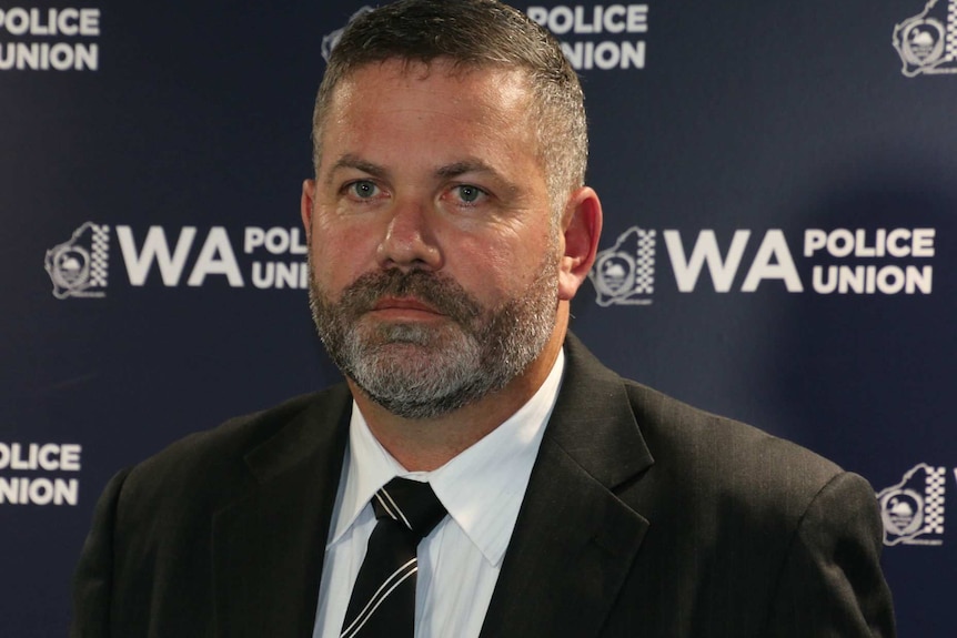 Harry Arnott standing in front of a police union banner