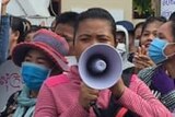 Ung Chanthoeun in a pink tracksuit and megaphone protests in Phnom Penh with other garment factory workers.