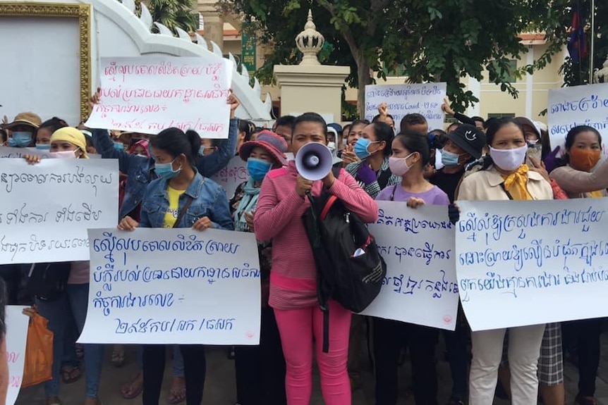 Ung Chanthoeun in a pink tracksuit and megaphone protests in Phnom Penh with other garment factory workers.