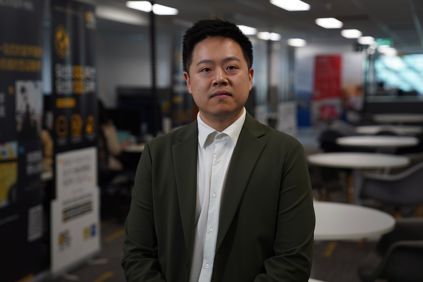 Tin Zhu stands in an office wearing a suit jacket