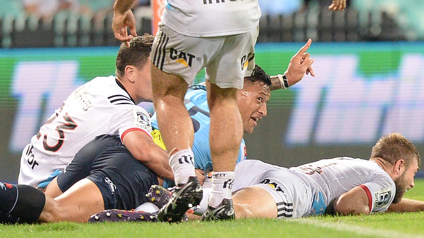 Israel Folau raises his hand in celebration while lying on the turf after scoring a try for the Waratahs against the Crusaders.
