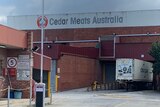 A truck is parked in an industrial driverway in front of a brick building marked 'Cedar Meats Australia'.