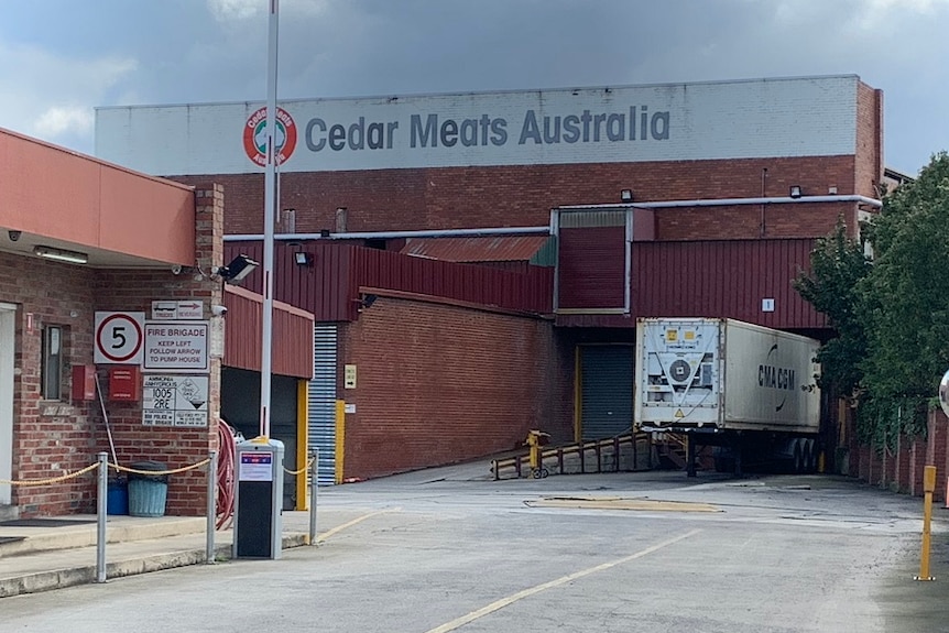 A truck is parked in an industrial driverway in front of a brick building marked 'Cedar Meats Australia'.