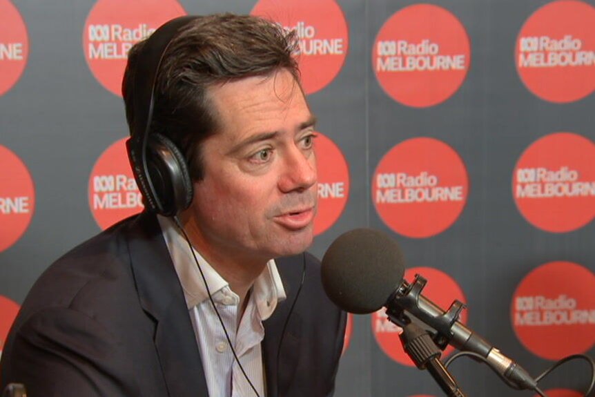 Gillon McLachlan wears headphones and speaks into a microphone during an interview in the ABC Radio Melbourne studio.