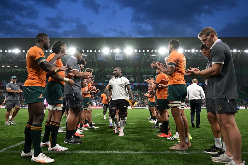 Wallabies players applaud Fijian players in a guard of honour after their Rugby World Cup match.