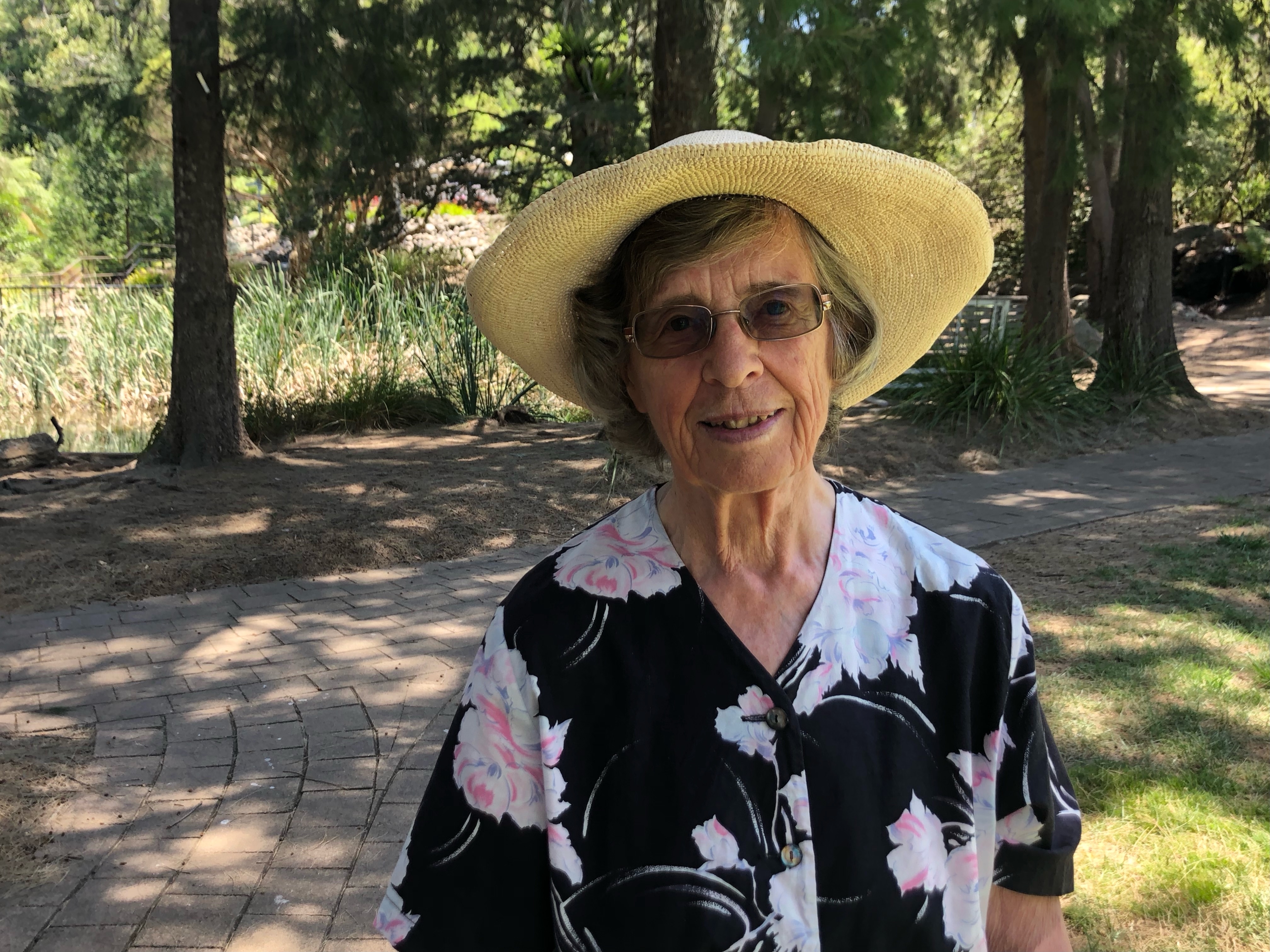 An older woman in a sun hat smiles.
