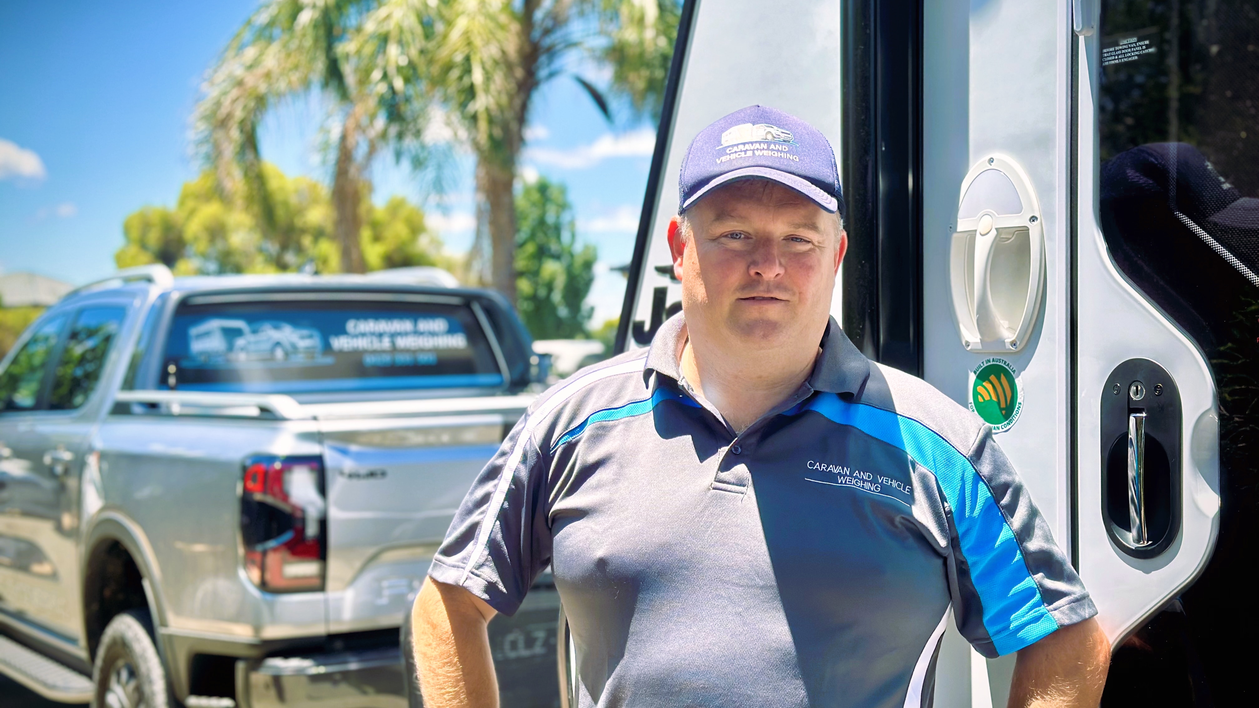a man stands in front of a ute and caravan