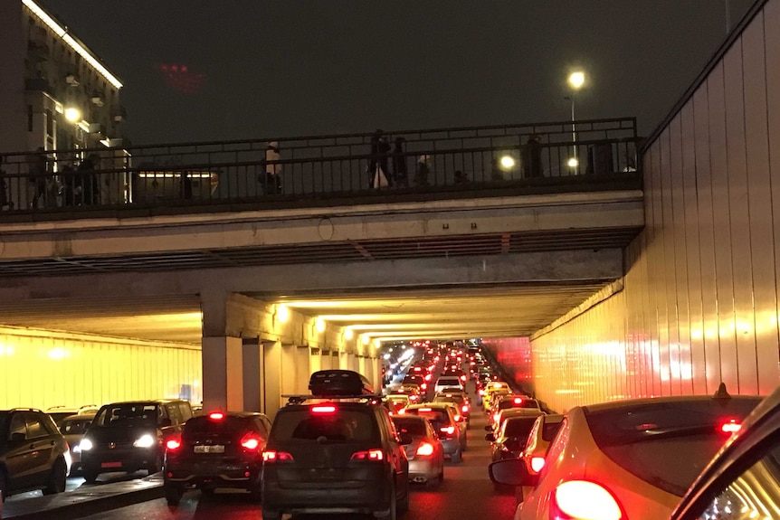 cars gridlocked at night underneath a bridge