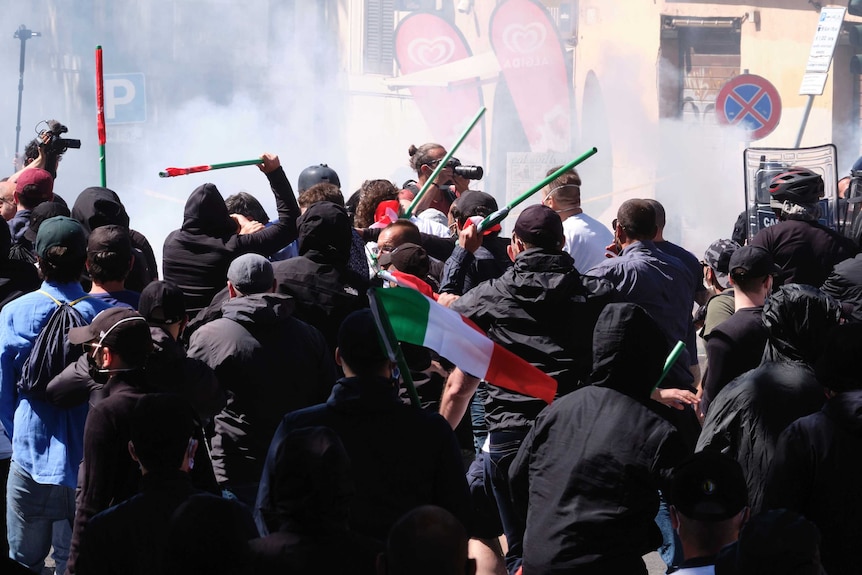 A crowd wave batons as an Italian flag can be seen above the crowd.