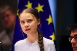 Swedish climate activist Greta Thunberg speaks in front of an EU flag.