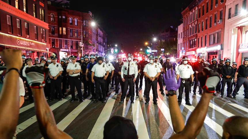 Protesters take a knee on Flatbush Avenue in front of a line of New York City police officers.