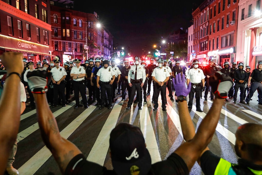 Protesters take a knee on Flatbush Avenue in front of a line of New York City police officers.