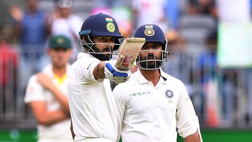 Indian batsman Virat Kohli points his bat at the stands as teammate Anjinkya Rahane looks on.