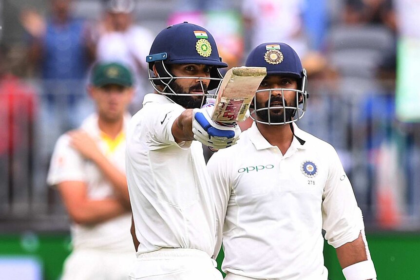 Indian batsman Virat Kohli points his bat at the stands as teammate Anjinkya Rahane looks on.