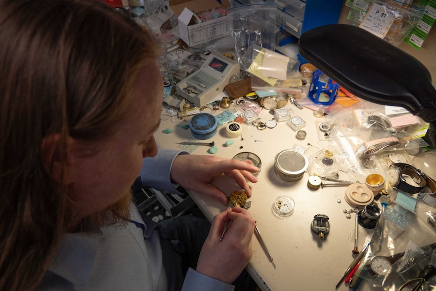 Picture of a man repairing a watch at a desk