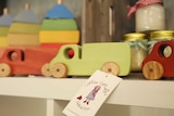 Brightly-coloured wooden toy trucks on a shelf.