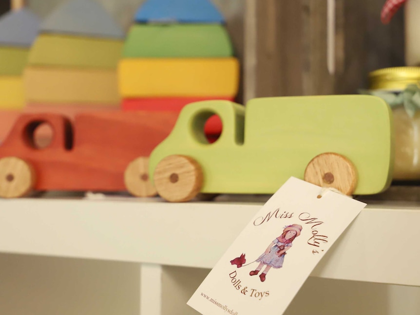 Brightly-coloured wooden toy trucks on a shelf.