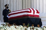 Bill and Hillary Clinton in black stand on Supreme Court steps in US-flag draped coffin of Ruth Bader Ginsburg.