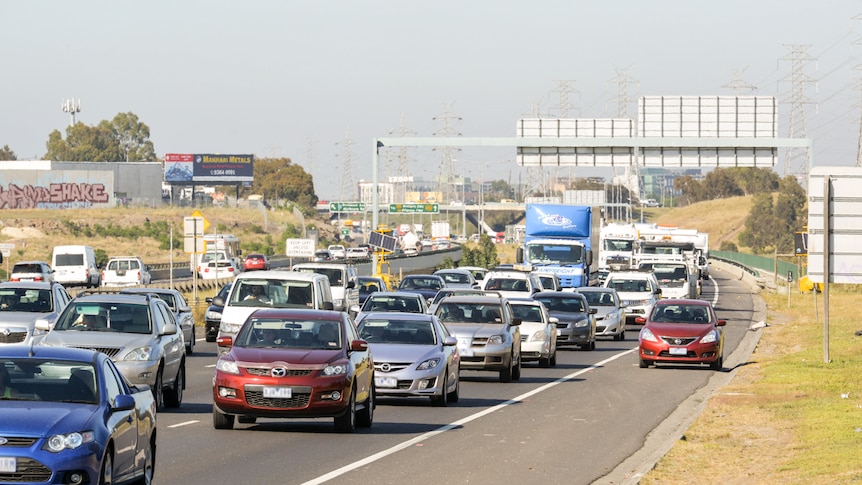 A busy highway. Car pulled over in emergency lane.