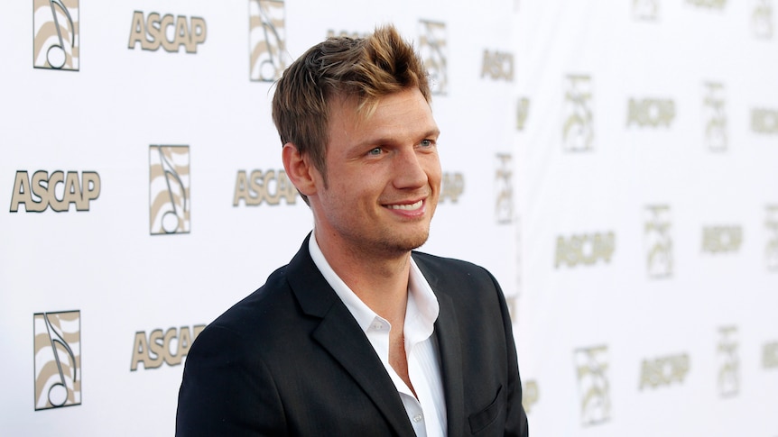 Nick Carter in a suit stands on the red carpet at the ASCAP awards. 