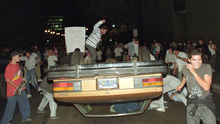 People surround an upturned car at night