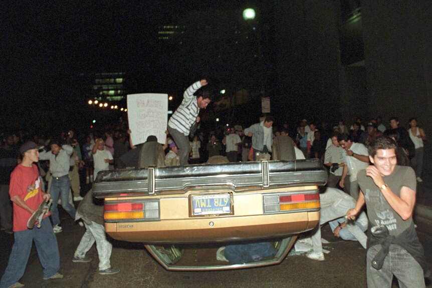 People surround an upturned car at night