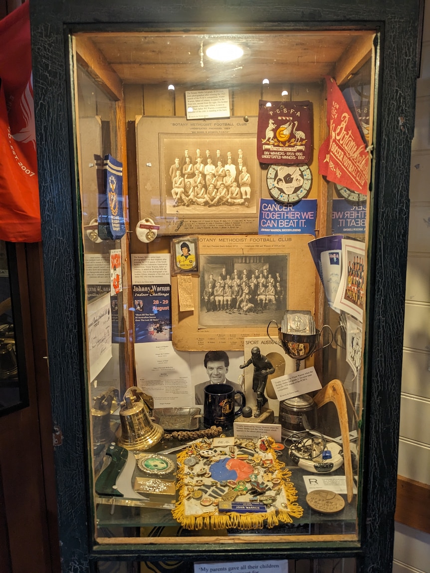 A cabinet with photos and trophies and other Australian soccer memorabilia