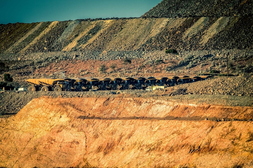 A line of mining trucks at a mine in WA