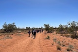 A group of people walks down a rough dirt track looking for a missing man in a remote part of WA.