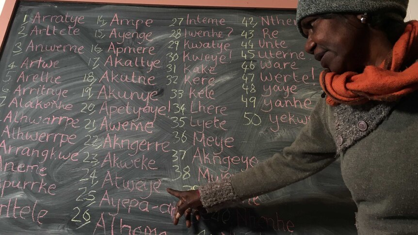Veronica Turner teaches an Arrernte class with a chalkboard filled with words in language in Alice Springs