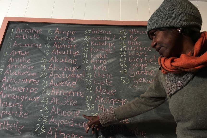 Veronica Turner teaches an Arrernte class with a chalkboard filled with words in language in Alice Springs