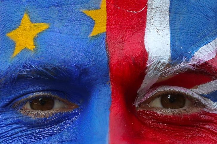 A person's face is seen close-up with the EU flag painted on the left and the UK flag painted on the right.