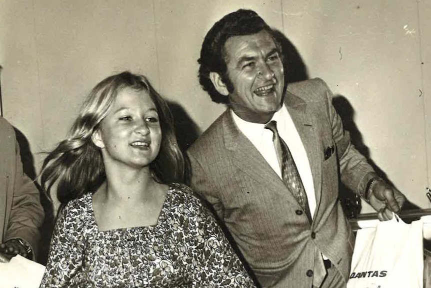 Sue Pieters-Hawke and Bob Hawke carry luggage at an airport.