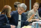 Penny Wong covers a microphone while speaking to a government official