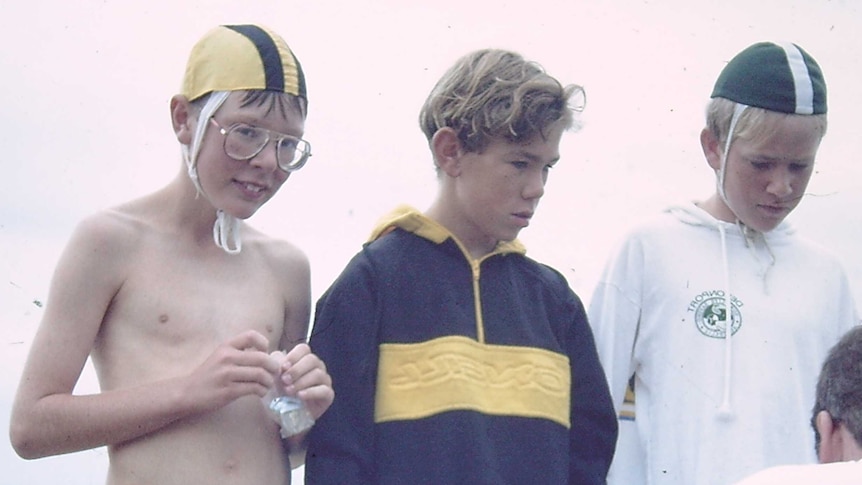 three young boys on the beach at nippers, only one looks to camera - that's Justin, in very 1980s specs and a cloth bathing cap