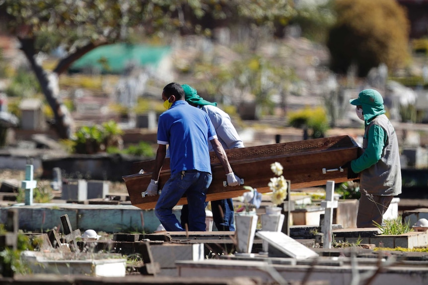 Cemetery workers carry a coffin.
